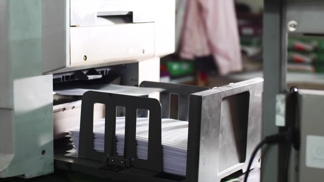 Publishing business and industrial. Laser print machine industrial big printer printing on big sheets of paper in typography office. Sheets putting on tray moving from printer.