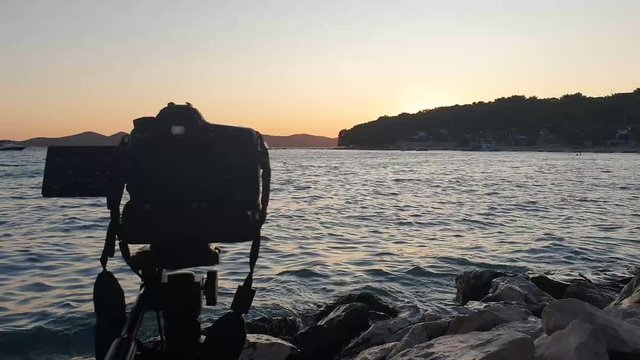 Camera standing on dark tripod shooting timelaps at sunset. Review of a camera shooting time laps.