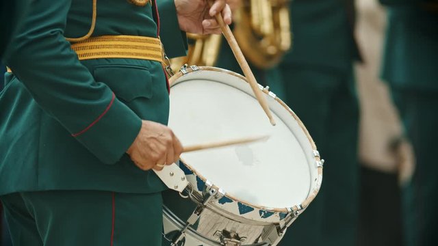 A wind instrument military parade - a person in green costume playing drums outdoors