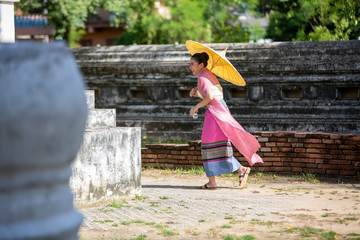Obraz premium Portrait of an Asian Women in Thai Lanna and Shan Traditional Clothes are Standing and hold umbrella Against Thailand Temple