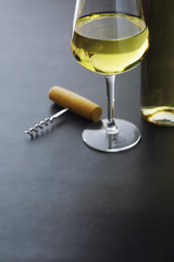 Transparent bottle of white dry wine on the table. White wine glass on a wooden background.