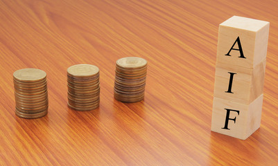 Alternative investment Funds or AIF on wooden block letters with Stack of currency coins.
