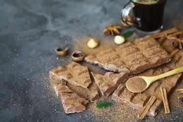 A bar of milk chocolate on the table. Chocolate with nuts and cinnamon.