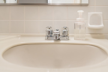Washbasin and hand soap in the white bathroom of the hotel
