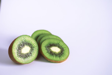 A kiwi fruit is sliced on a white background