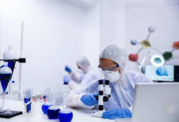 Scientist in modern research laboratory adjusting her microscope