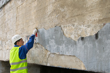city worker clean walls of graphics and inscriptions, with a metal brush, before painting