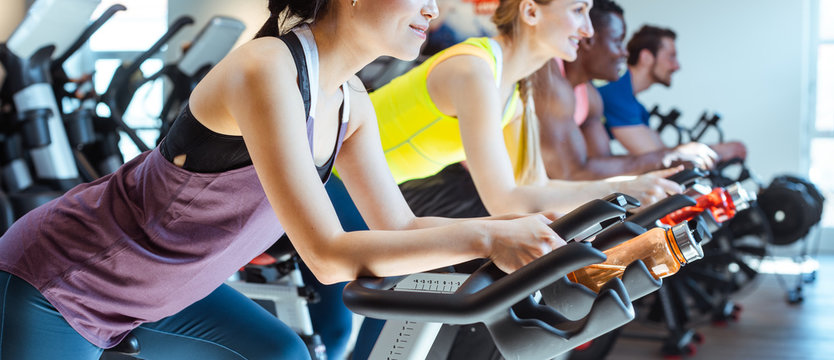 Asian Woman And Her Friends On Fitness Bike In Gym