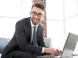 Young businessman using laptop and smiling