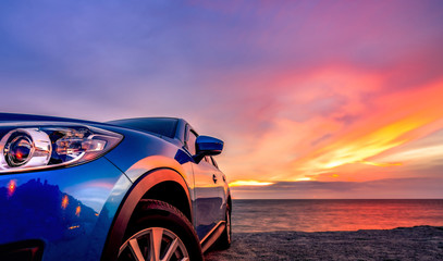 Blue compact SUV car with sport and modern design parked by beach at sunset. Hybrid and electric car technology. Car parking space. Automotive industry. Car care business background. Beautiful sky.