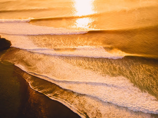 Aerial view of big stormy waves at warm sunset
