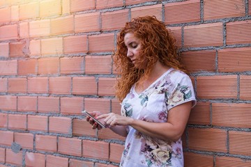 woman with her mobile phone on the brick wall