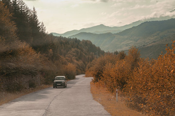 Asphalt road and cars in the mountains with cloudy sky on the background.. - 286062537