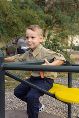 Fototapeta na wymiar Child boy ride on a carousel in the playground
