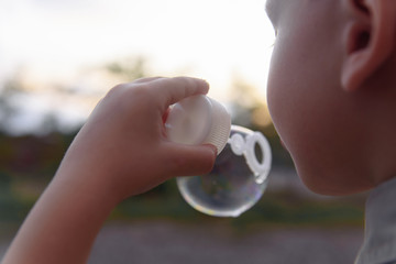 Fototapeta premium Little boy blowing bubbles. The concept of lifestyle and childhood.