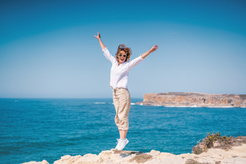 Beautiful young woman with a happy smile in a white shirt on the ocean in Portugal