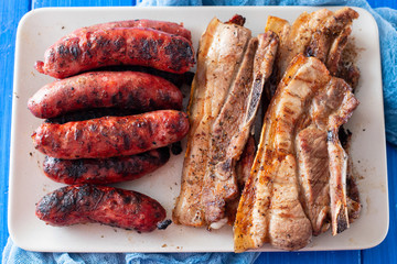 grilled meat and sausages on dish on wooden background