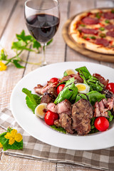 Hot salad of liver and ham with quail eggs, cherry tomatoes and herbs with balsamic sauce on white boards. Free space for text. Menu cover