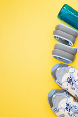 Flat lay of sport and fitness equipment on yellow background with copy space.