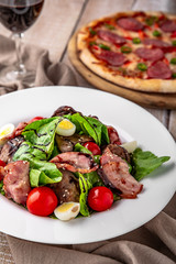 Hot salad of liver and ham with quail eggs, cherry tomatoes and herbs with balsamic sauce on white boards. Free space for text. Menu cover