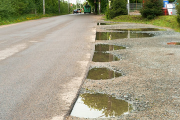 Puddles on the edges of the asphalt road. Road after rain.