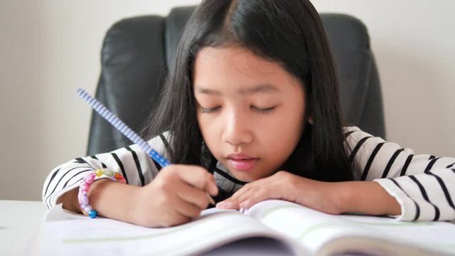 Little Asian girl doing homework with happiness for self learning and home education concept select focus shallow depth of field