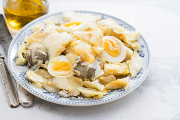 cod fish with onion, eggs and olive oil on dish