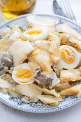 cod fish with onion, eggs and olive oil on dish