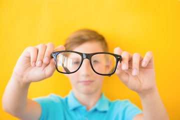 Closeup portrait of young man with glasses. He has eyesight problems and is squinting his eyes a little bit. Selective focus