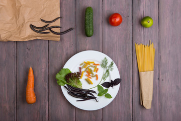 Fresh pasta ingredients in eco paper bags - spaghetti pasta, carrot, basil, tomato and other vegetables on plate