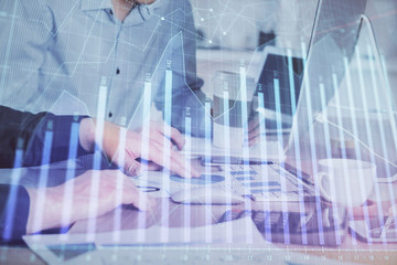 Multi exposure of chart with man typing on computer in office on background. Concept of hard work.