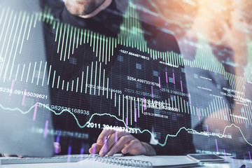 Forex graph with businessman working on computer in office on background. Concept of analysis. Double exposure.