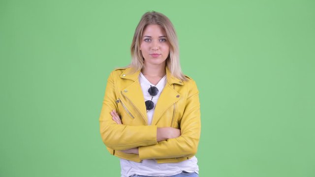 Happy young rebellious blonde woman smiling with arms crossed