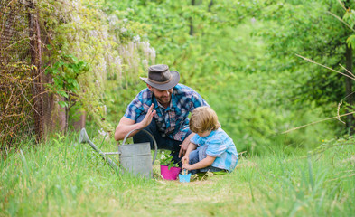 Naklejka na ściany i meble happy earth day. Family tree nursering. father and son in cowboy hat on ranch. watering can, pot and hoe. Garden equipment. Eco farm. small boy child help father in farming. Transplanting plant