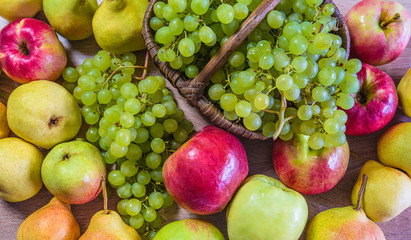 Beautiful fresh ripe fruits background. Red apples, yellow pears and white grapes