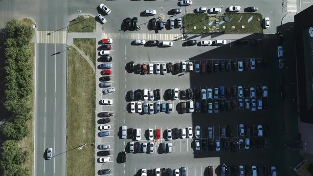 A view from above to the process of car parking. Heavy traffic in the parking lot. Searching for spaces in the busy car park. Parking advice. Cruising for parking in busy business center