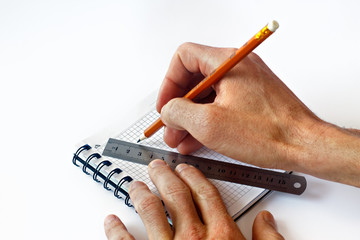 Male hand writes in a notebook. A man holds a pen and ruler in his hand and is going to draw in a notebook. Close-up. Copy space