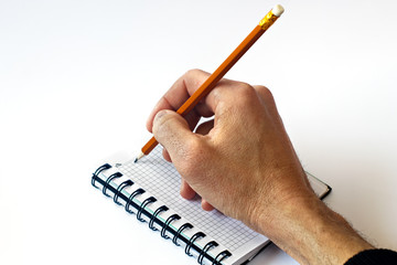 Man's hand writes in a notebook. A man holds a pen in his hand and is about to make a note in a notebook. Close-up. Copy space