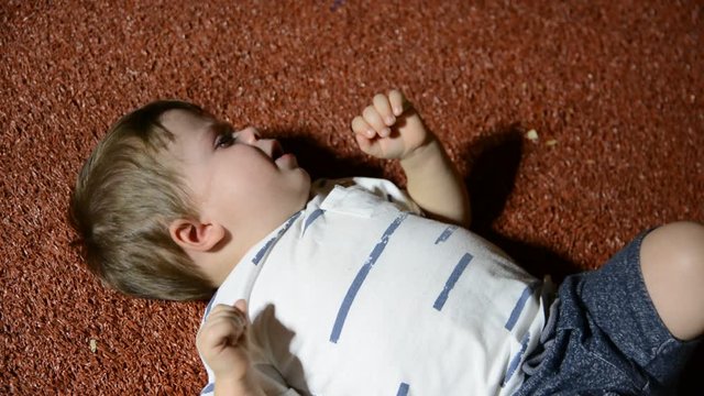 child naughty on the floor in the evening park. Low light, high gain.