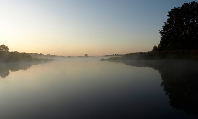 Fototapeta na wymiar sunrise above a river on foggy summer morning, the sky reflections in the water, misty reflection in steaming water, Salaca river, Latvia 