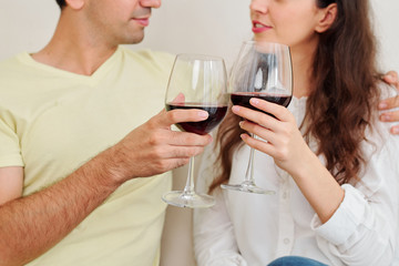 Cropped image of young couple enjoying romantic evening at home with tasty red wine