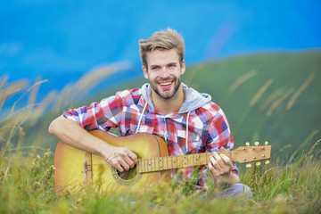 Playing music. Man musician with guitar on top mountain. Inspired musician. Summer music festival outdoors. Silence of mountains and sound of guitar strings. Hipster musician. Inspiring environment