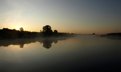sunrise above a river on foggy summer morning, the sky reflections in the water, misty reflection in steaming water, Salaca river, Latvia 