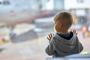 Two year old boy at the airport looking at plane