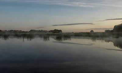Obraz na płótnie Canvas blur fantastic foggy river with green grass in the sunlight. Salaca river, Burtnieks Lake, Latvia