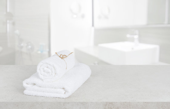 White towels on table in defocused bathroom with copy space