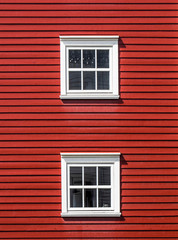 Two floors of windows on a red wooden facade