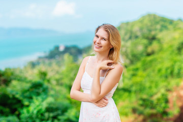 Fototapeta na wymiar Smiling happy woman is standing at summer tropical island background.