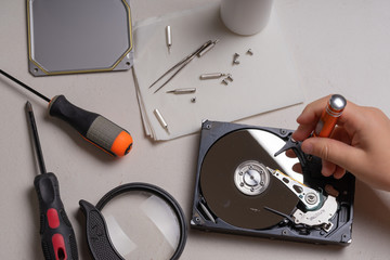 A teenager disassembles the hard drive of a computer to study its device.