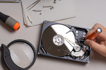 A teenager disassembles the hard drive of a computer to study its device.